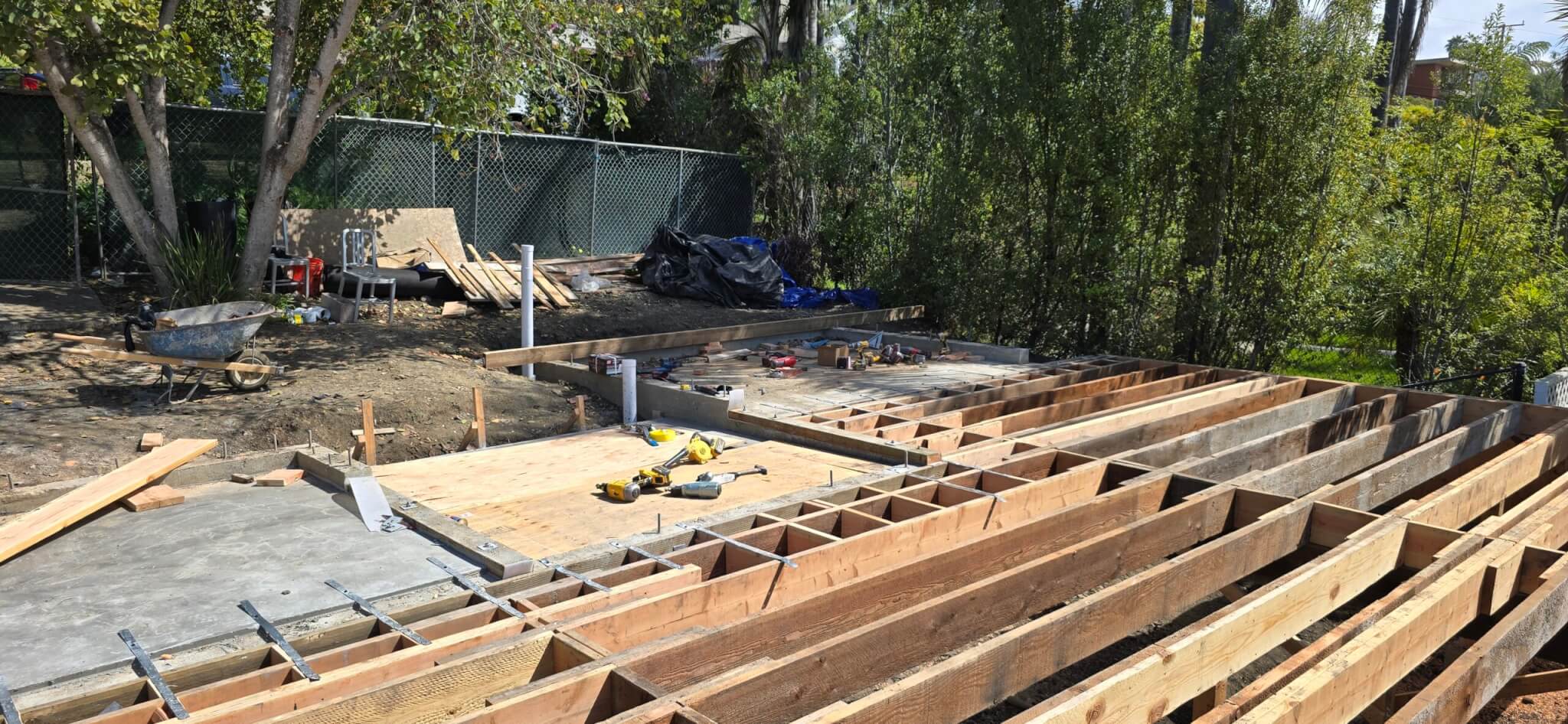 Alt Text<br />
A construction site in Summerland, California, showing a newly laid concrete foundation alongside a partially framed wooden floor joist system for a new building.